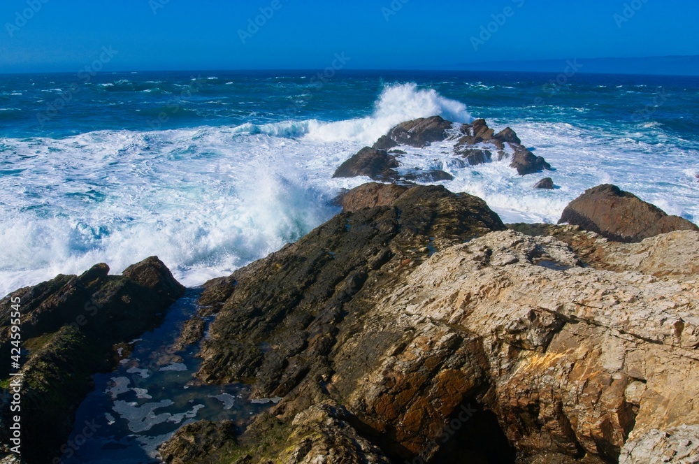 Ocean waves crash over boulders along the California coast.