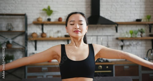 Portrait of young asian woman doing yoga fitnesss exercise namaste asana and stretching at home. Living room apartment kitchen background photo