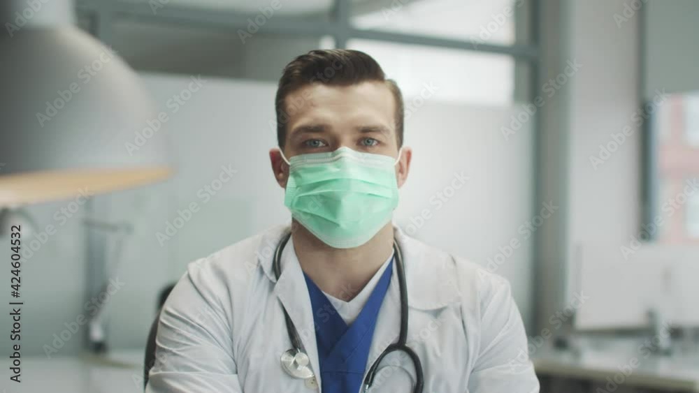 Portrait of a reliable authentic doctor in a medical mask in the hospital office. A direct look at the camera. Combating the spread of coronavirus infection. Portrait of a reliable authentic doctor in a medical mask in the hospital office. A direct look at the camera. Combating the spread of coronavirus infection.