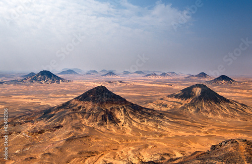 Fototapeta Naklejka Na Ścianę i Meble -  The Black Desert is a region of volcano-shaped and widely spaced mounds, distributed along about 30 km in western Egypt between the White Desert in the south and the Bahariya Oasis in the north. 
