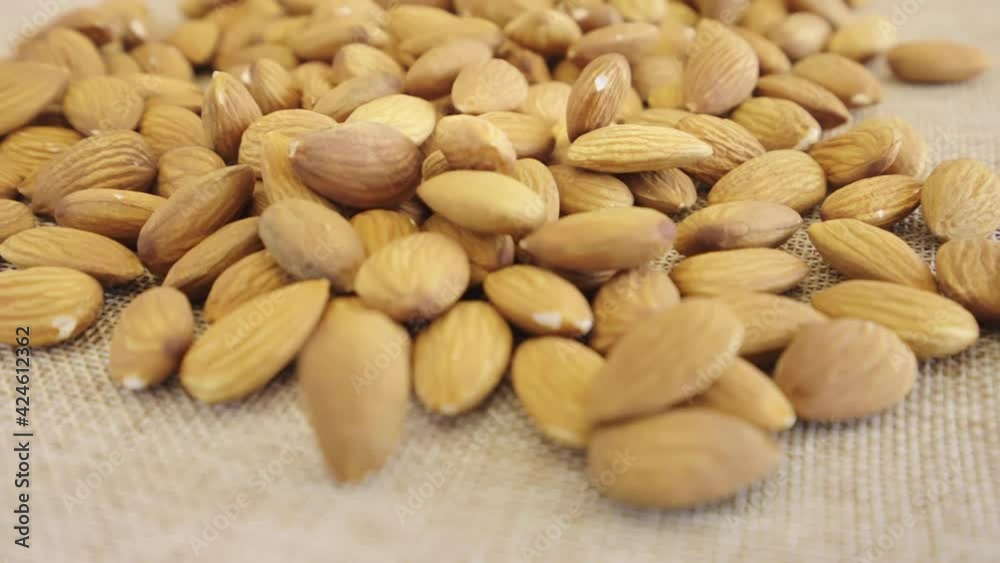 Close up almonds seed rotate on brown fabric, Slow motion almond kernels rotation with brick background, Front view almond nuts rotating, Concept whole grains of food for healthy. Close up almonds seed rotate on brown fabric, Slow motion almond kernels rotation with brick background, Front view almond nuts rotating, Concept whole grains of food for healthy.
