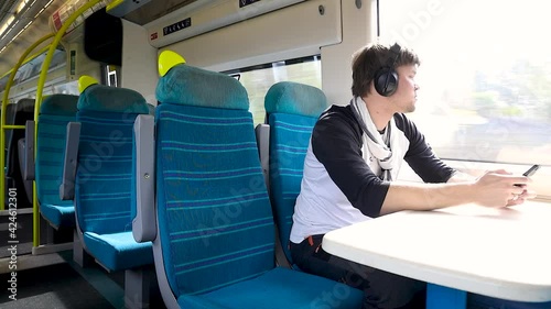 Male passenger with the phone riding the train moving across England, UK