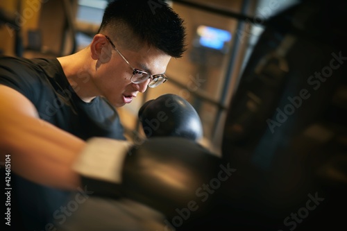トレーニングジムでキックボクシングをするアジア人男性