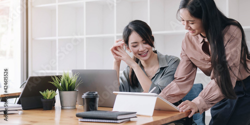 Two young woman designer in casual wear working with laptop and discussing new project at modern office.