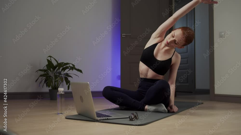 Girl doing body bends while sitting on the exercise mat. Long shot Girl doing body bends while sitting on the exercise mat. Long shot