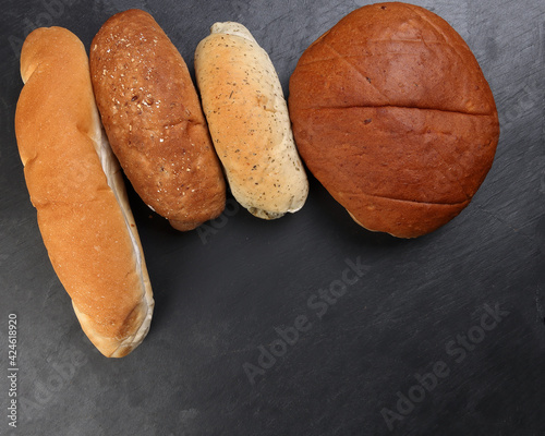 Freshly baked bread loaf bun roll round long mix verity copy text space border frame black background photo