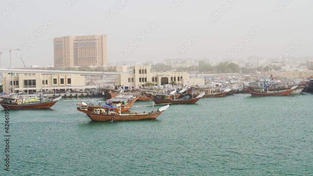 Traditional Dhow Boats Sailing At Dubai Creek With City Buildings In The Background In Dubai, UAE. - wide shot Traditional Dhow Boats Sailing At Dubai Creek With City Buildings In The Background In Dubai, UAE. - wide shot