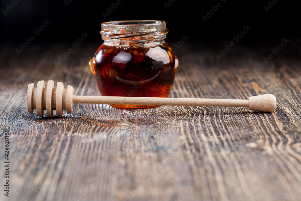 a spoon for honey together with high-quality bee honey a spoon for honey together with high-quality bee honey