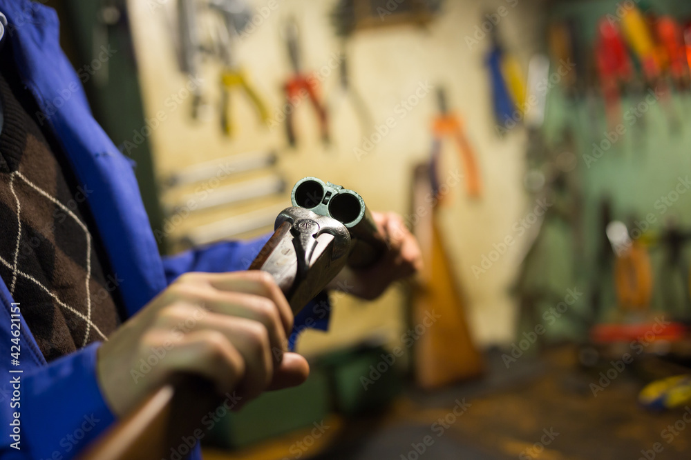 Naklejka premium Close-up of break-action of horizontal double-barreled hunting shotgun in hands of gunsmith in workshop.