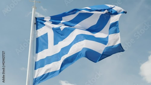 Slow motion of Greek flag rippling on the wind against blue sky.