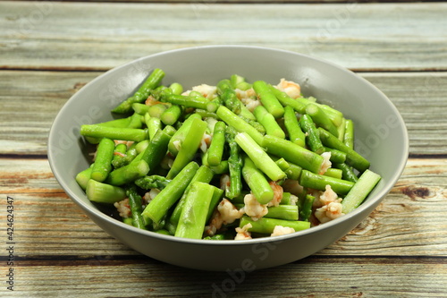 Traditional fried and stirred cutting fresh asparagus with chopped peeled shrimp serving on the plate. Famous appetizer salad menu in Asia restaurant.  