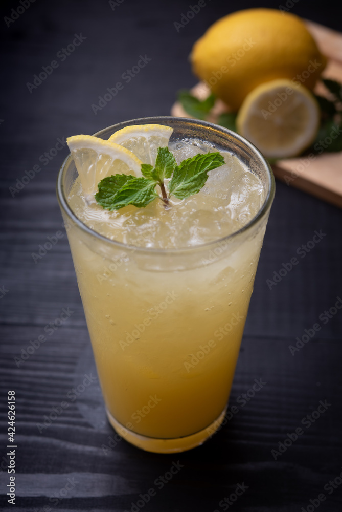 glass of iced lemonade with fresh lemon and mint by lemon reamer on wood glass of iced lemonade with fresh lemon and mint by lemon reamer on wood