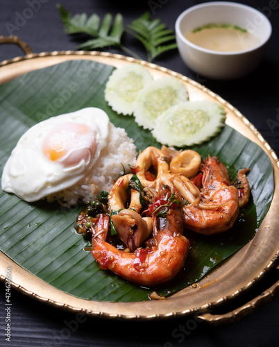 rice and stir-fried seafood (shrimps and squid) with basil , fired egg on the table,Thai style food