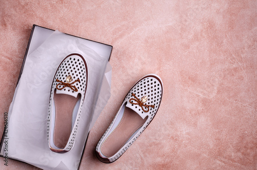 Fotografija Light women's shoes with a bow and perforation on a brown background