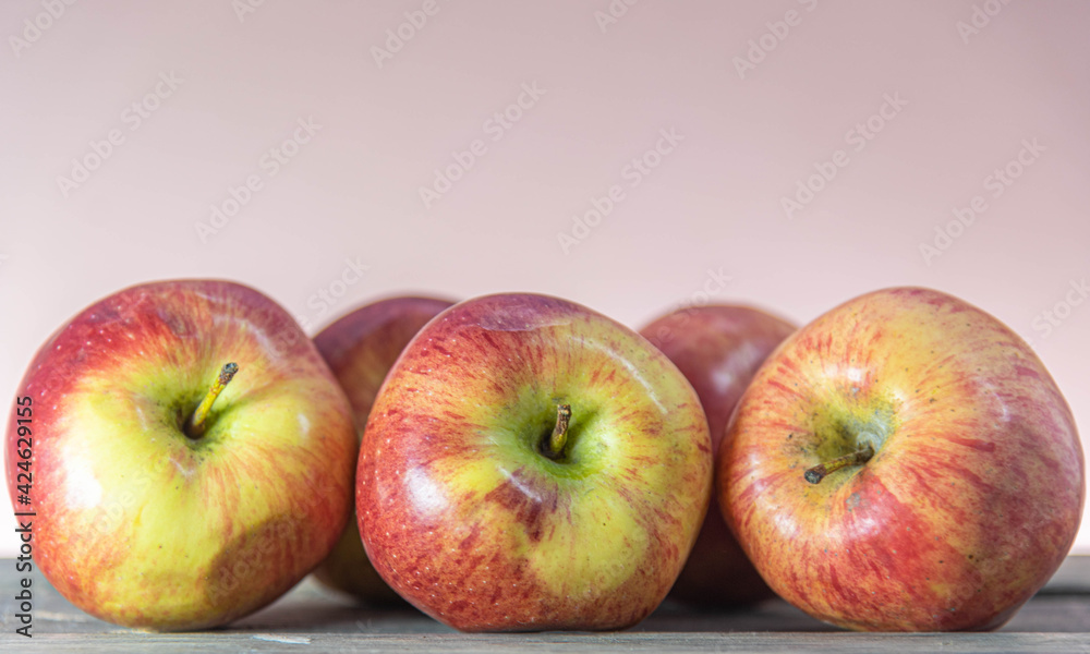 Red apple fruits on wooden surface on neutral background. Red apple fruits on wooden surface on neutral background.