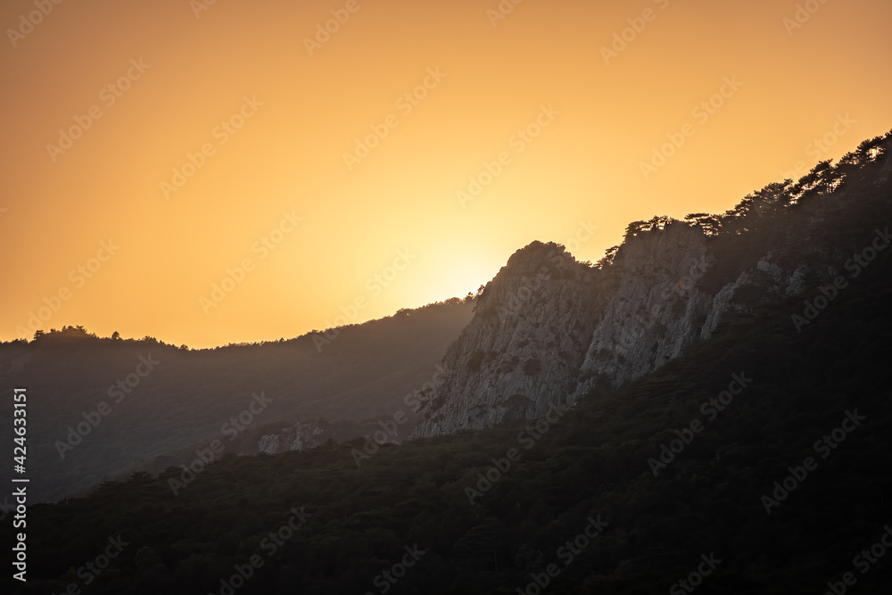 Fototapeta premium Sunset in the mountains among the green trees