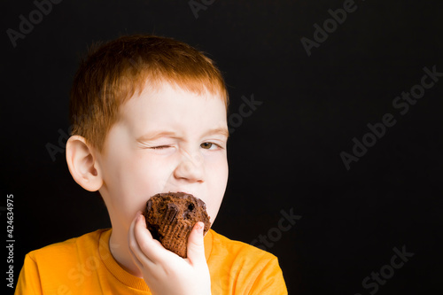 Fotografija a beautiful red-haired boy with a chocolate cupcake