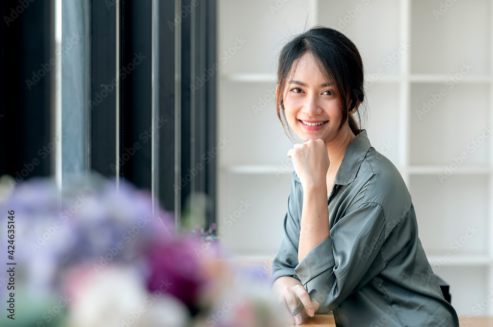Portrait of young beautiful asian woman smiling and looking at camera while sitting at the table. Portrait of young beautiful asian woman smiling and looking at camera while sitting at the table.