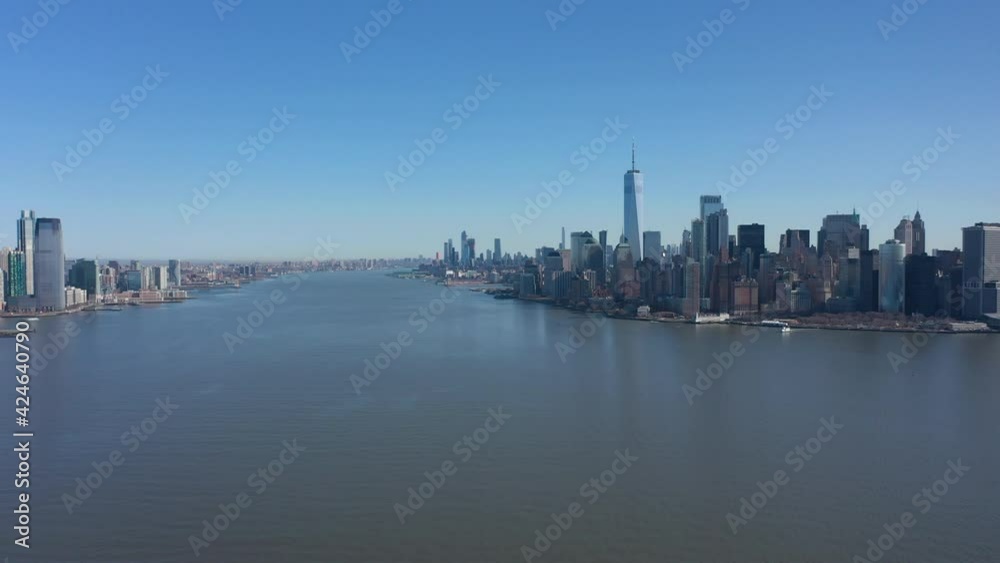 An aerial view over New York Harbor on a sunny day with blue skies. The drone camera facing lower Manhattan dolly out and pan left.. An aerial view over New York Harbor on a sunny day with blue skies. The drone camera facing lower Manhattan dolly out and pan left..