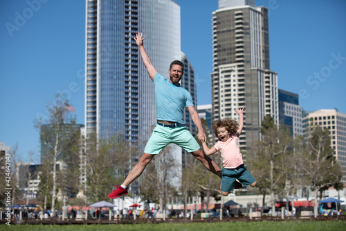 Excited father and son jumping on urban city background. Concept of friendly family.