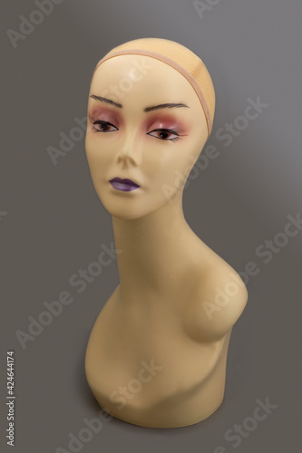 Mannequin full face of a woman's head with makeup without hair on a gray background. Fashion accessories store model for jewelry, wigs, hats, glasses, etc.