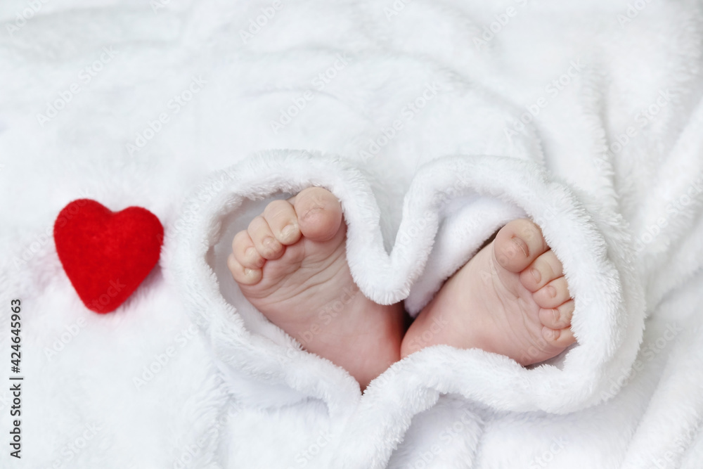 Tiny, cute, bare feet, covered with a white blanket in the shape of a heart. Copy space concept of happy family, family love relationship, motherhood and childhood, love, tenderness, valentine's day Tiny, cute, bare feet, covered with a white blanket in the shape of a heart. Copy space concept of happy family, family love relationship, motherhood and childhood, love, tenderness, valentine's day