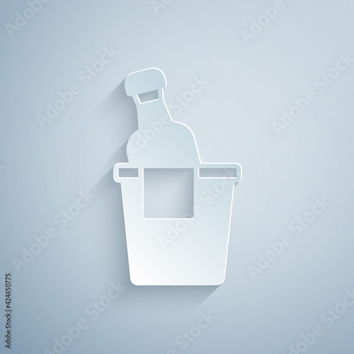 Paper cut Bottle of champagne in an ice bucket icon isolated on grey background. Paper art style. Vector