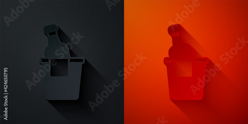 Paper cut Bottle of champagne in an ice bucket icon isolated on black and red background. Paper art style. Vector