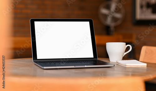 Mockup blank screen laptop with coffee and notebook on the table, Taken from the front.