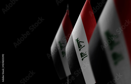 Small national flags of the Iraq on a black background