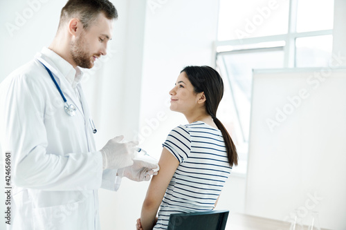 male doctor in a white coat injecting a woman's hand in a health hospital covid vaccination
