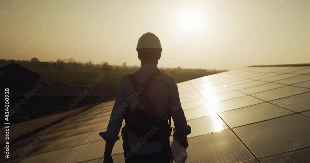 Maintenance assistance technical worker in uniform is smiling satisfied of his work after checking operation and efficiency performance photovoltaic solar panels on roof at sunset. clean green energy