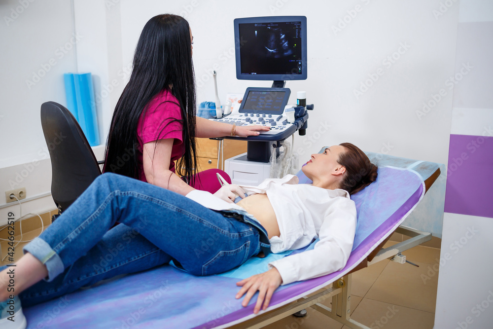 A young woman lies on a couch, a doctor appointment, an ultrasound scan of the abdominal organs is performed on the girl, the doctor examines the patient A young woman lies on a couch, a doctor appointment, an ultrasound scan of the abdominal organs is performed on the girl, the doctor examines the patient