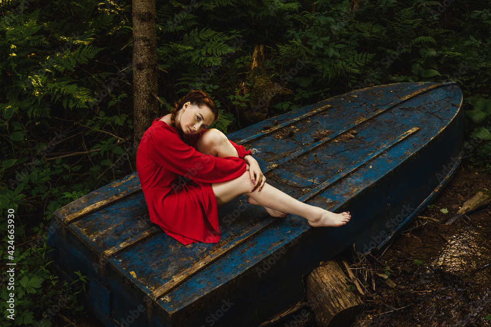 Fototapeta premium The young woman sitting on blue boat.