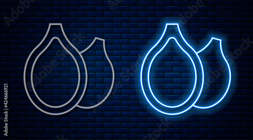 Glowing neon line Pumpkin seeds icon isolated on brick wall background. Vector