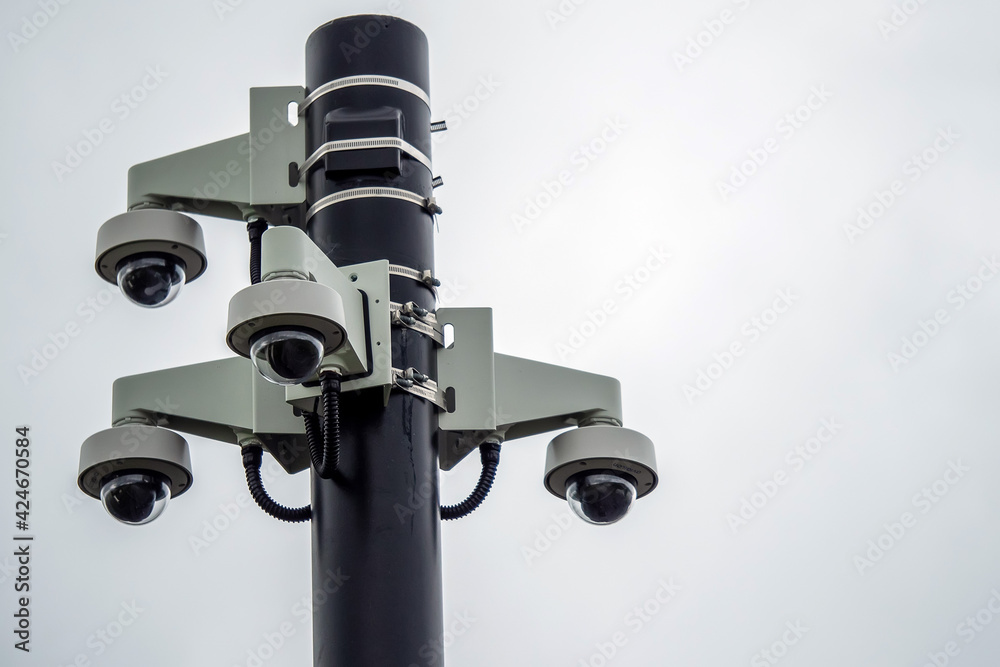 Fototapeta premium Four spherical CCTV cameras fixed on a black metal pole. Security and safety concept.