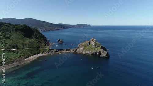 Aerial arriving at Gaztelugatxe is islet on coast of Biscay Spain Basque Country it is connected to mainland by a man-made bridge and on top of island stands a hermitage named Gaztelugatxeko Doniene photo