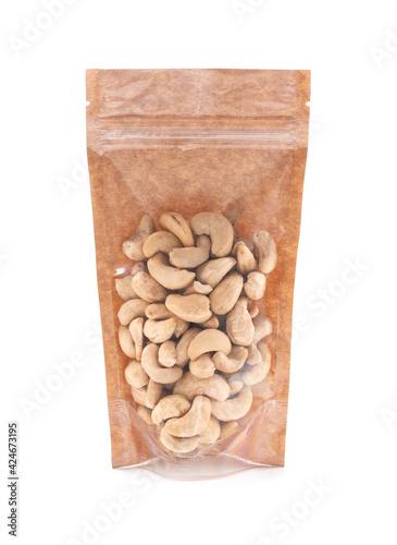 Cashews in a brown paper bag. Doy-pack with a plastic window for bulk products. Close-up. White background. Isolated.