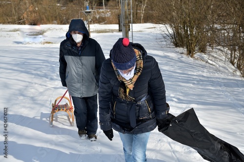 Men and women are pulling sledge up the hill in the winter in the snow 