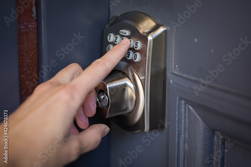 Caucasian female hand pressing buttons door entry key pad open entrance security lock protect home front airbnb photo