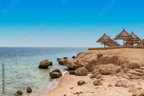 Beautiful sandy beach with rocks and Parasol in Red Sea, Egypt, Africa.