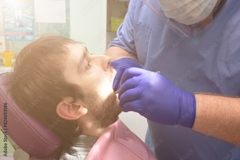 Team of dental surgeons performs surgery on teeth. in a modern clinic. Young dentist. Teamwork. Tooth doctor orthodontist surgeon doing medical operation on root canals. Stomatology office. Team of dental surgeons performs surgery on teeth. in a modern clinic. Young dentist. Teamwork. Tooth doctor orthodontist surgeon doing medical operation on root canals. Stomatology office.