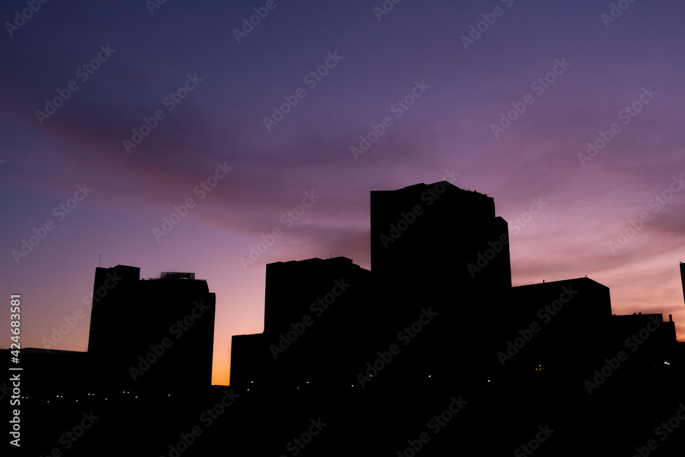 Dawn in the city, vivid purple sky and tall buildings in silhouette