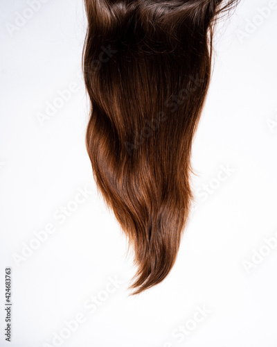 Dark hair curls lie on white background