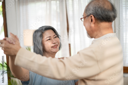 Asian senior couple dancing together in free time at the living room.