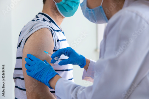 Female doctor applying a vaccine on a male patient .