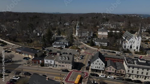 Drone forward over Downtown Hingham, Massachusetts, toward a busy town center, showing Boston skyline, skyscrapers in the distance. St. Paul's Church shown. North, central, south and lincoln streets. photo