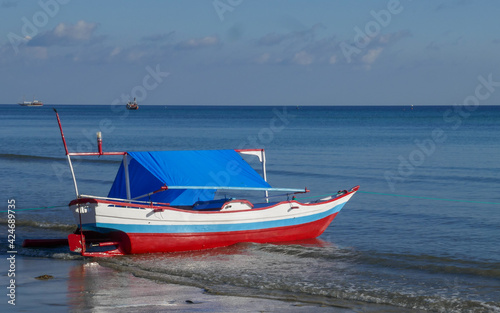 Minimalist view of small colorful wooden fishing boat with calm sea and horizon in Tanah Beru, Bulukumba, South Sulawesi, Indonesia
