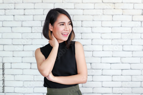 Portrait of young and cute Asian woman standing against white brick wall crossed arms in self-confident pose and smile with friendly and happy face.