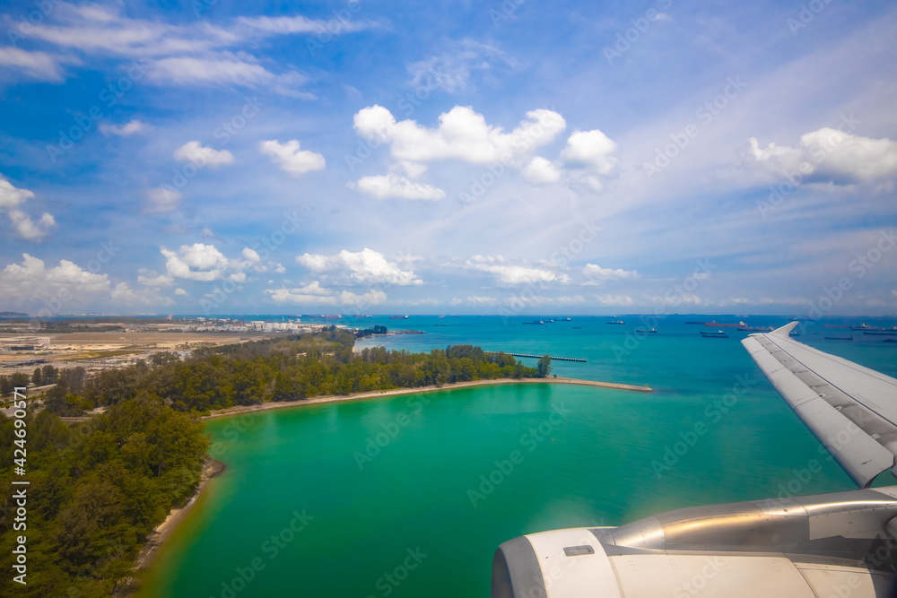 view of the tropical ocean coast from the porthole of a landing plane